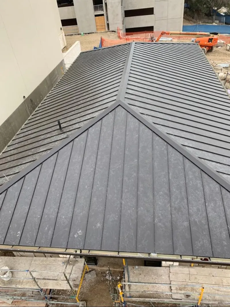 Commercial metal roof construction with crane equipment in Covington